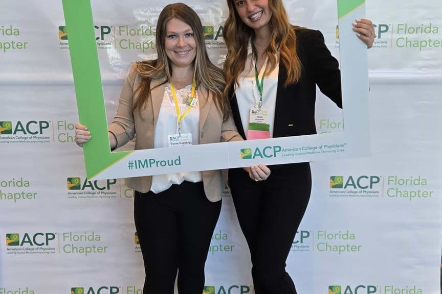 Two members holding the I.M. Proud frame at a chapter meeting