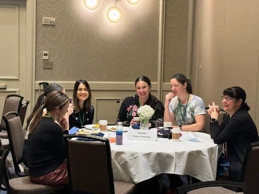 Members seated around a table in conversation at a chapter event
